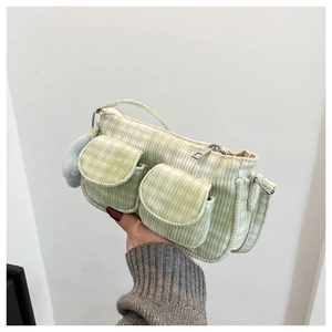 Détail du sac bandoulière en velours côtelé vert clair avec poches cargo et pompon bleu