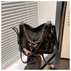 Détail du sac plissé noir avec boucle papillon métallique et décoration de chaîne argentée