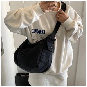 Detail of black crescent canvas crossbody bag with side utility pocket and silver buckle