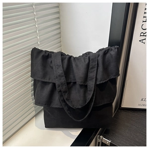 Detalle del borde con volantes y la textura de lona negra duradera del bolso tote grande