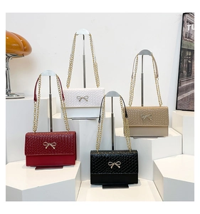Close-up of elegant small square bags with woven texture, metal bows and gold chains