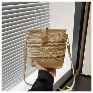 Détail du sac seau en paille tressée avec bandoulière en cuir et boucle dorée chic