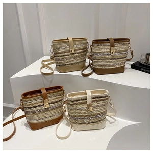 Detail of woven straw bucket bags in four colors with leather straps and metal buckles