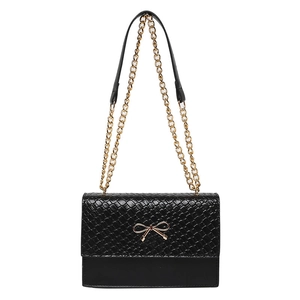 Minimalist black woven flap shoulder bag with gold bow clasp and elegant chain strap