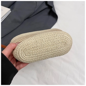 Detalle del fondo del bolso de paja trenzada con textura densa y correa marrón delgada