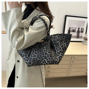 Side view of large leopard print tote bag carried by a model in a stylish home setting
