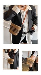Bolso de paja tipo cubo con rayas negras y una fina correa de cuero marrón para el hombro
