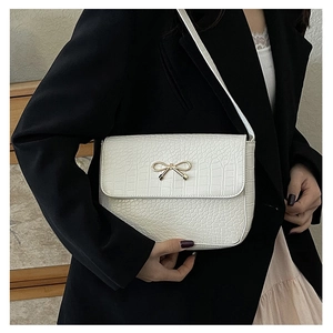 Détail du sac blanc à motif crocodile avec fermoir nœud doré et bandoulière fine