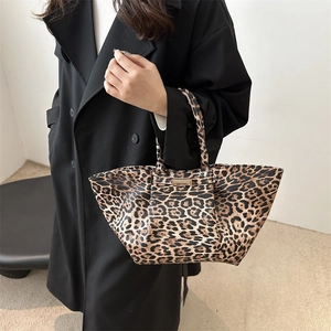 Vintage leopard print tote bag with metal plaque shown on a model in black coat