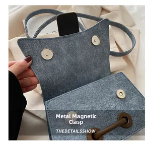 Detail of light blue textured crossbody bag with silver magnetic snap buckle closure