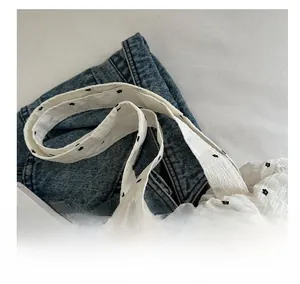 Détail d'un sac cabas en mesh blanc à volants avec motifs floraux noirs et large anse