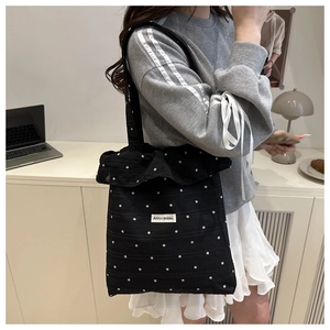 Détail du sac cabas noir à pois avec bord à volants et étiquette AGOGO ORIGINAL