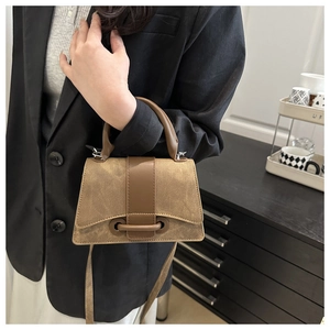 Detail van vintage trapeze tas met bruine textuur en metalen gesp met ronde ring