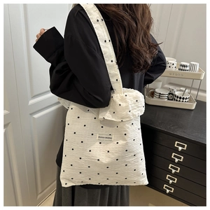 Détail d'un sac cabas en tissu gaufré à volants avec motifs floraux et étiquette