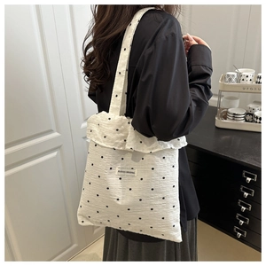 Gros plan d'un sac cabas en mousseline blanche avec imprimé floral noir et bord volanté