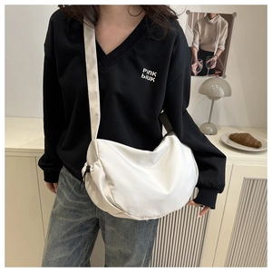 Detail view of a white nylon crescent crossbody bag featuring black drawstring lock closure