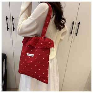 Détail d'un sac cabas rouge à fleurs avec bords volantés et écusson en tissu