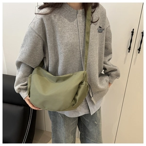 Detail view of olive green nylon crescent bag with adjustable wide shoulder strap on model