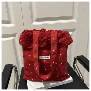 Détail d'un sac en mousseline rouge à fleurs avec texture plissée et étiquette de marque