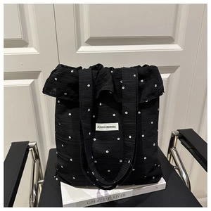 Détail d'un sac cabas plissé noir avec broderies florales et bords volantés