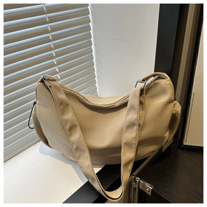 Detailed close-up of a beige nylon crossbody bag featuring metallic rings and drawstrings