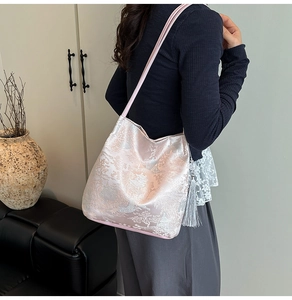 Detalle de bolso de hombro jacquard rosa con bordado de paisaje y borlas plateadas