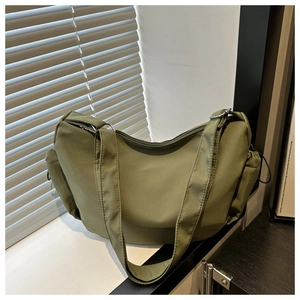 Detail of dark green nylon dumpling bag showing wide strap and drawstring side pocket