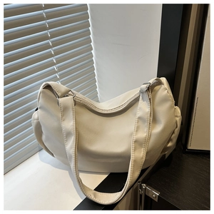 Detail of a minimalist beige nylon crescent bag featuring wide straps and silver metal buckle