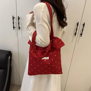 Grand sac cabas rouge à fleurs avec nœud papillon et volants, porté à l'épaule