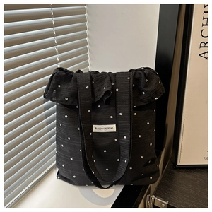 Détail du sac cabas noir à volants avec broderie florale et étiquette de marque tissée
