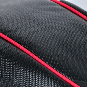 Macro detail of motorcycle tail bag featuring carbon fiber texture and red piping trim