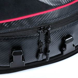 Macro detail of motorcycle tail bag featuring carbon fiber texture and red piping trim
