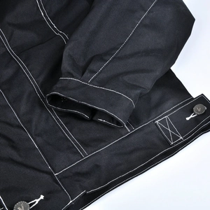 Détail d'une veste de moto imperméable avec surpiqûres contrastées et boutons logo V