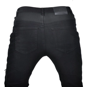 Detail view of the elastic ribbed waistband and leather logo patch on black motorcycle jeans