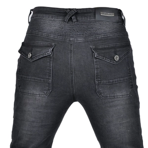 Close-up of motorcycle jeans featuring accordion stretch panels and metal brand logo plate