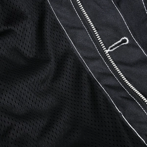 Détail de la veste de moto en maille avec broderie blanche L sur tissu noir robuste