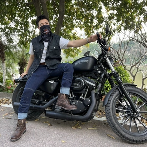 Homme portant un gilet de moto noir en coton huilé sur une moto lourde en extérieur