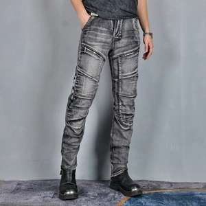 Detail of motorcycle jeans with gray wash finish, protective knee pleats and metal zippers