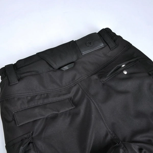 Detail of waterproof motorcycle pants showing black twill fabric and a leather waist logo