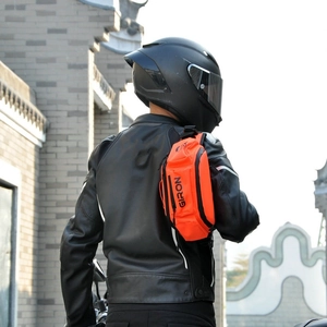 Détail d'un sac bandoulière moto orange vif GIRON porté par un motard en veste de cuir