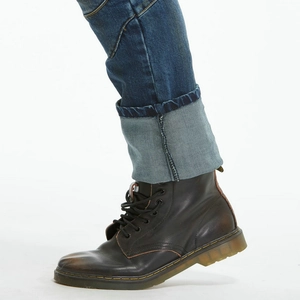 Detail of blue denim motorcycle jeans with large rolled hem and vintage brown leather boots