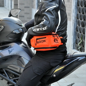 Détail d'une sacoche de moto étanche orange avec logo GIRON portée par un motard