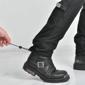 Detail of adjustable drawstring hem on black motorcycle pants paired with biker boots