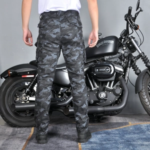Rear view of camouflage motorcycle pants with flap pockets next to a motorbike