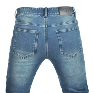 Detail of blue motorcycle denim pants featuring heavy washing and reinforced stitching