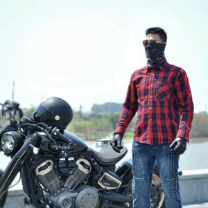 Outdoor shot of a rider in red and black plaid protective motorcycle shirt by the river