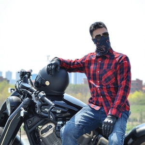Blue motorcycle neck gaiter with orange graffiti worn by a rider on a cruise bike
