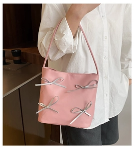Close-up of pink bucket bag featuring four silver metallic 3D bow decorations on the front