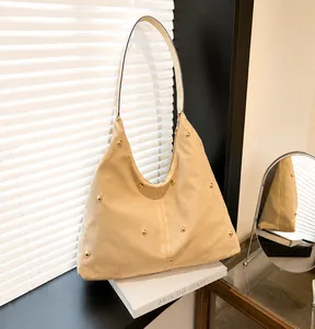 Detail of beige canvas tote bag with gold rivet studs and minimalist triangle silhouette