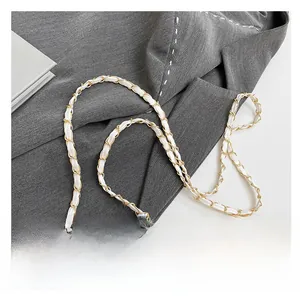 Close-up of woven chain strap with gold metal and white leather for luxury shoulder bag